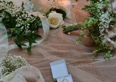 Anelli nuziali in scatola bianca accanto a bouquet floreale e candele accese, matrimonio in Abruzzo