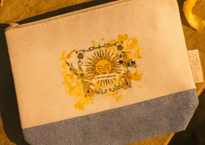 Pochette in tela personalizzata con logo del sole, rami d'ulivo e la scritta 'L'oro del Trabocchi'