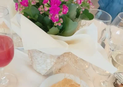 Centrotavola da matrimonio o evento con una piantina di Kalanchoe rosa e pane su un tavolo con bicchieri.