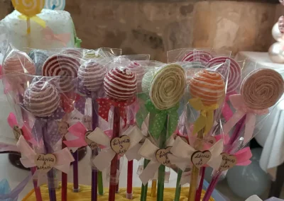 Pennette colorate a forma di lecca lecca, disposte in un vaso, con fiocchi e cartoncini personalizzati per il compleanno di Ludovica