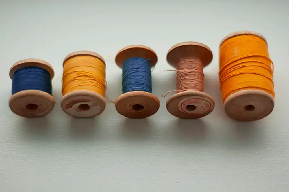 rocchetti di filo in legno - palette per cuciture su misura Cinque rocchetti di filo in legno allineati su piano chiaro, in colori diversi