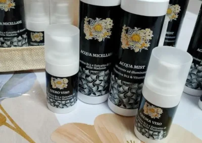 Dettaglio di flaconi di siero viso, crema viso e acqua micellare con etichette scure e logo del sole.